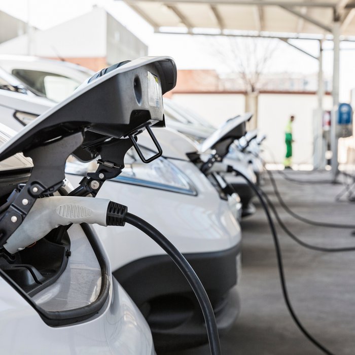 Mehrere Elektrofahrzeuge laden an Ladestationen auf einem Parkplatz.