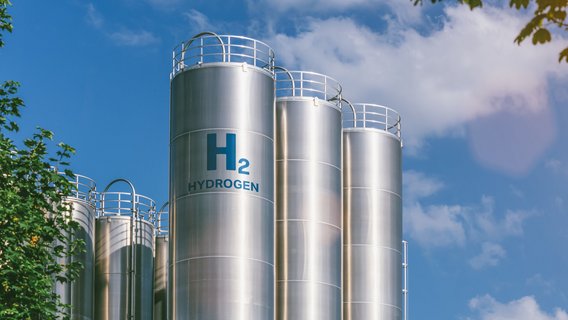 Silberne Tanks für die Speicherung von Wasserstoff vor blauem Himmel und Bäumen