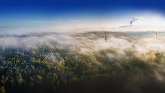weite Landschaft, die von einem dichten Nebel oder Dunst bedeckt ist.