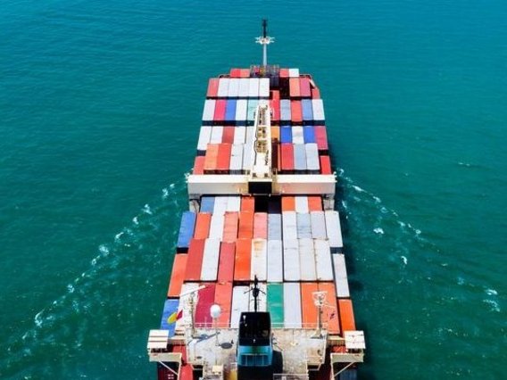 Luftaufnahme eines Containerschiffs auf offenem Meer, beladen mit bunten Frachtcontainern.