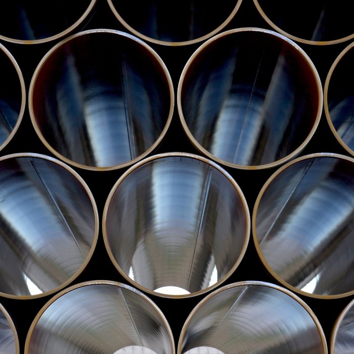Nahaufnahme von mehreren großen Metallrohren, die horizontal gestapelt sind